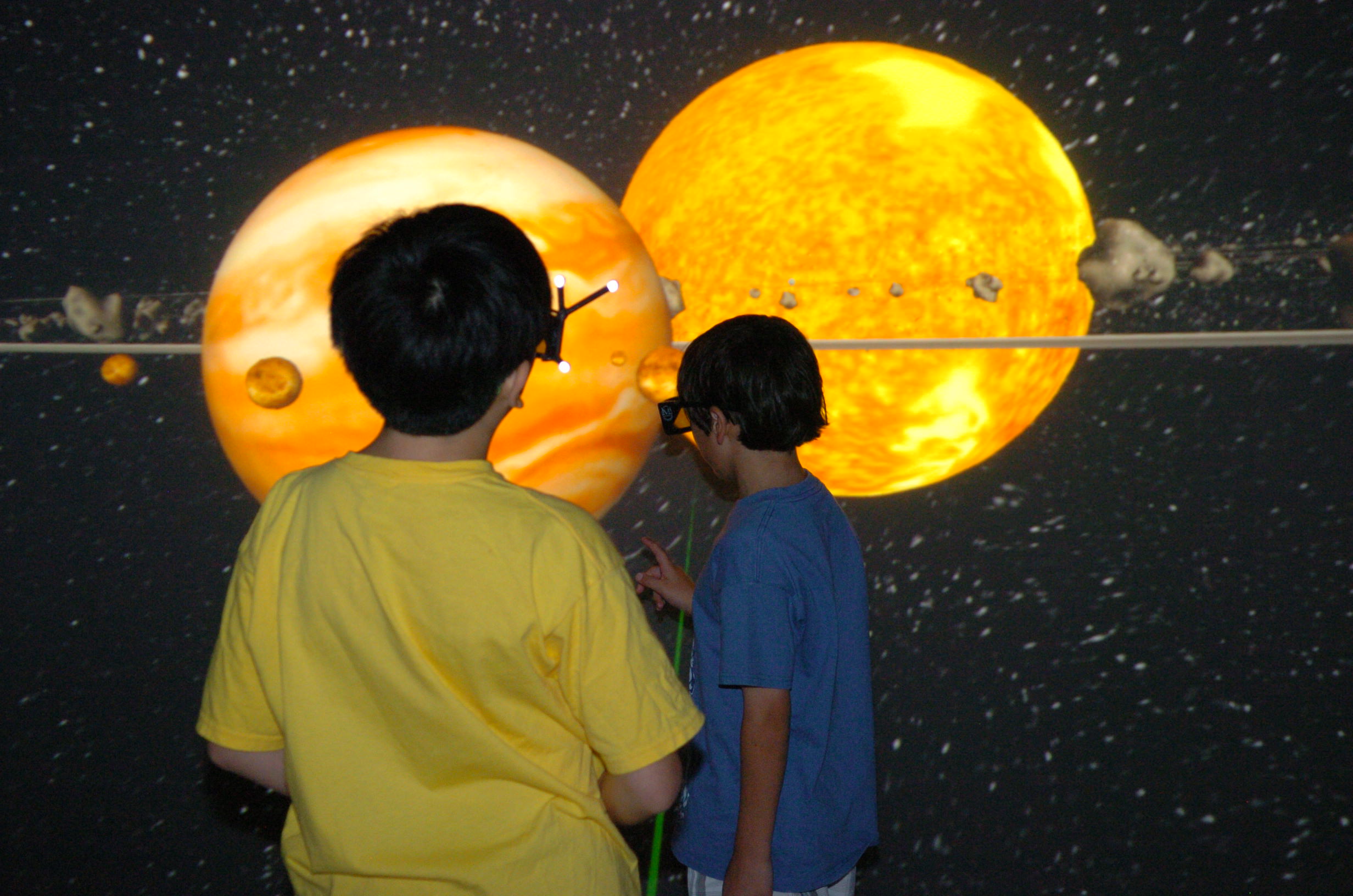 Sam from Korea and Korbyn from the United States experiencing the Solar System in 3D Interactive Cave Environment. Courtesy of JTM Concepts.